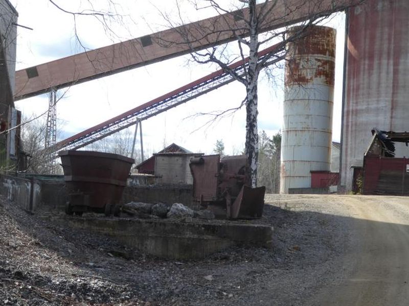 Two rusted ore cars in front of the conveyor gantry and silos at Yxsjoberg.